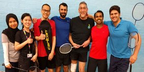 Group of staff members with badminton rackets, select to go to a list of clubs and societies.